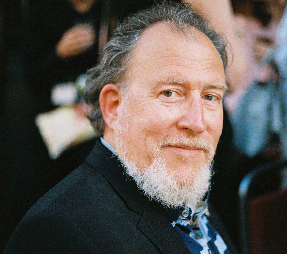 Matthew Asner grey beard wearing a dark suit