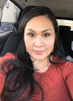 Woman with black hair wearing a red shirt sitting in the passenger seat of a car