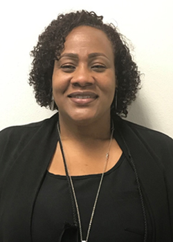 Woman with curly black hair wearing a black sweater over black shirt