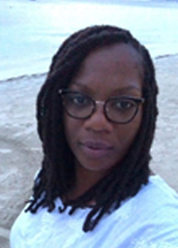 Woman with black braided hair wearing glasses standing on the beach