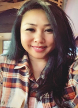 Woman with medium length, straight, black hair wearing an orange and blue plaid button up shirt