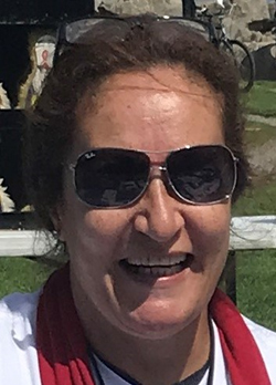 Woman with brown hair wearing silver rimmed sunglasses and a red scarf over a white shirt