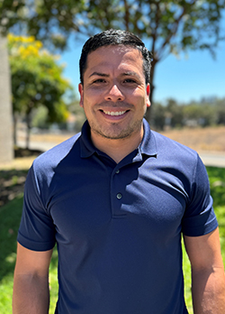 Man with short black hair wearing a blue polo shirt